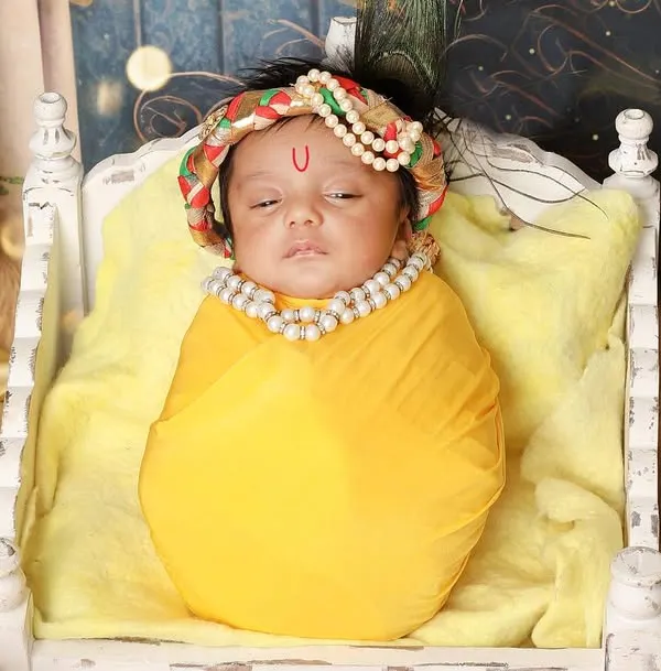 My 'Little Krishna' setup captures the divine essence of Janmashtami. Here, a newborn Kanha rests peacefully on a miniature cot, adorned with a pearl necklace and a traditional tilak.