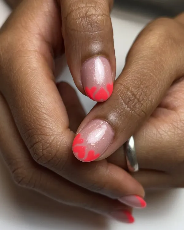 These tips might steal hearts. A fun twist on the French manicure with neon pink heart-shaped tips, perfect for a birthday or just for fun.