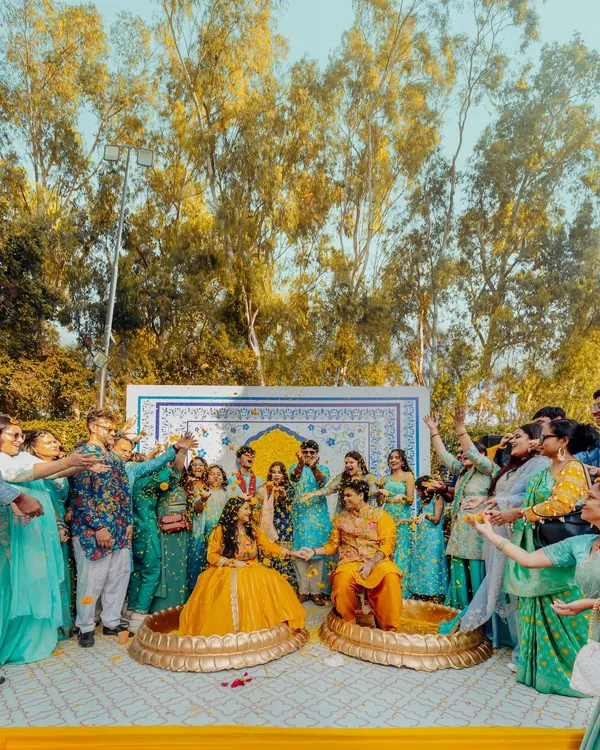 A wide shot of Abhinav and Paromita's Haldi ceremony, surrounded by family and friends. The vibrant yellow and blue decor at Tivoli Bijwasan creates a festive and joyful atmosphere.