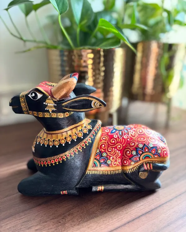 A seated Nandi sculpture exuding a calm, majestic aura. The classic combination of black, red, and gold detailing makes this a truly timeless piece of decor, perfect for adding a touch of spiritual elegance to your space.
