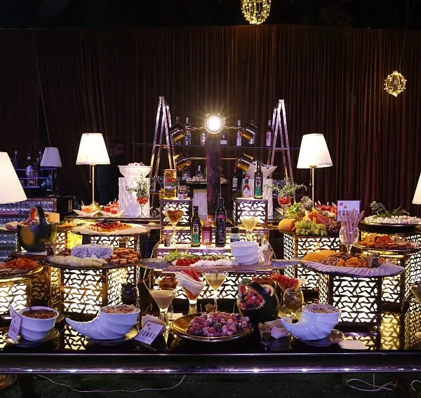 This is where the magic begins. A beautifully lit, lavish spread for a wedding reception, showcasing an array of appetizers, salads, and fruits. This setup demonstrates how I blend exquisite food with stunning presentation to create a focal point for your celebration.