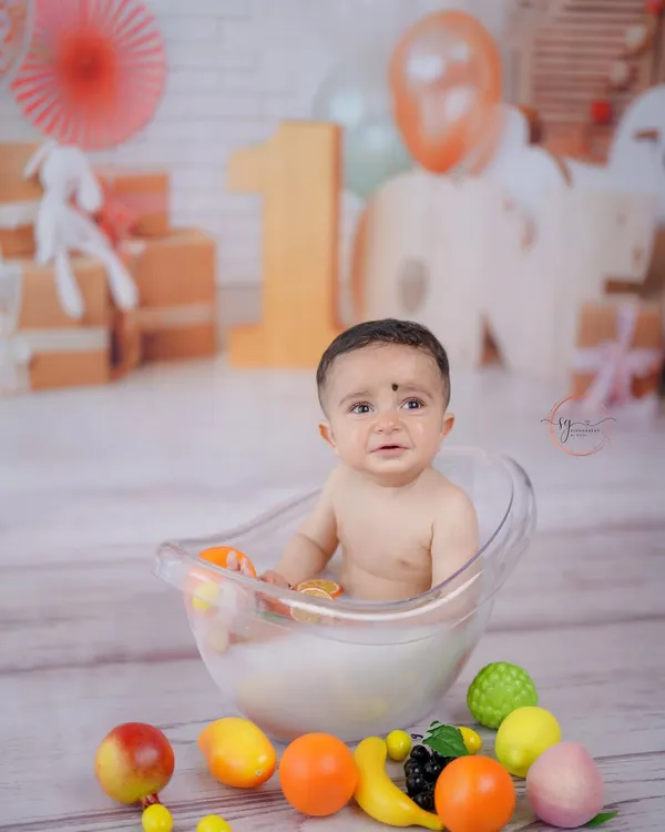A wider view of the fruity milk bath session, showing the complete setup with a blurred background that keeps the focus on the happy baby.