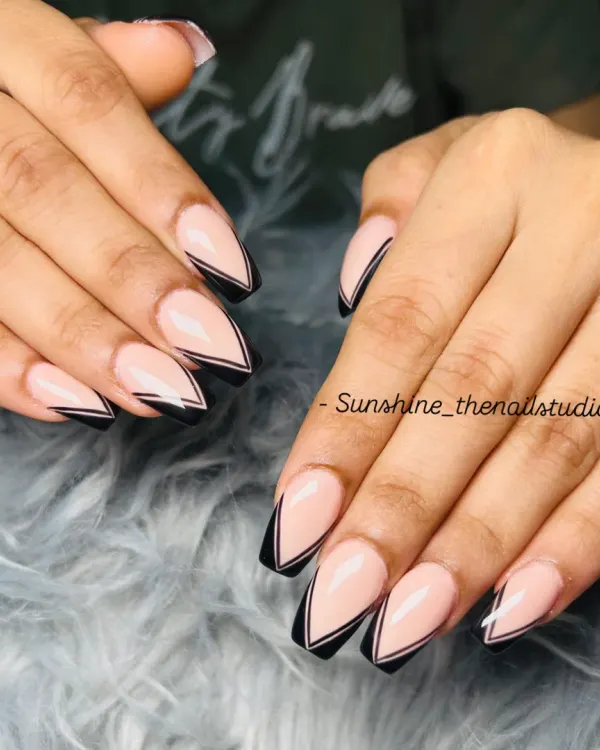 A sharp and modern take on the French manicure. This design features a double line V-shape French tip in black on long, coffin-shaped nails.