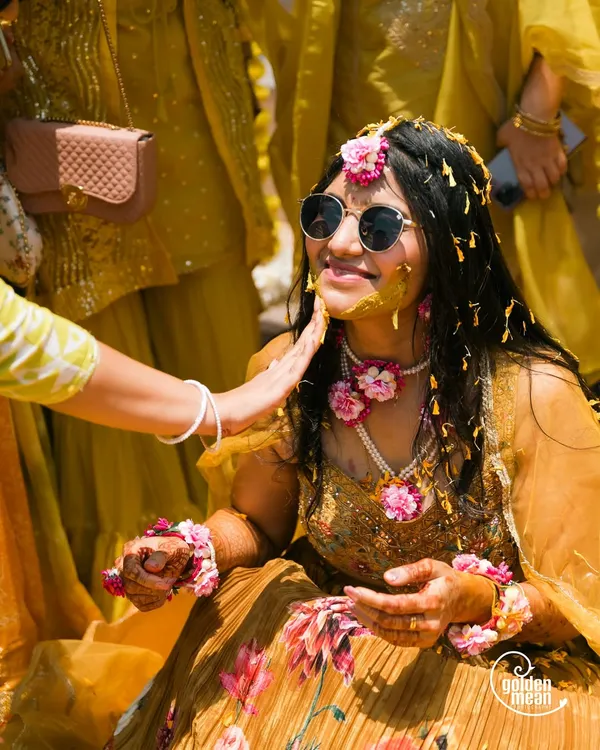A cool bride enjoying her Haldi ceremony. The mix of traditional turmeric paste and modern sunglasses perfectly captures her personality.