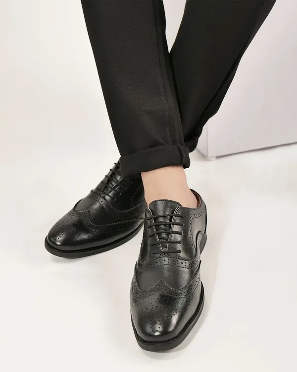 A detailed shot of a man wearing classic black leather brogues. The focus is on the shoe's design and high-quality material, perfect for a footwear brand.