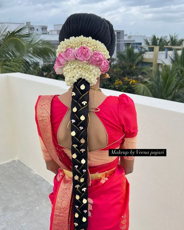 A stunning traditional bridal braid, perfect for a muhoortham. This hairstyle features a large jasmine and rose veni, with the braid itself decorated with intricate gold ornaments for a truly royal look.