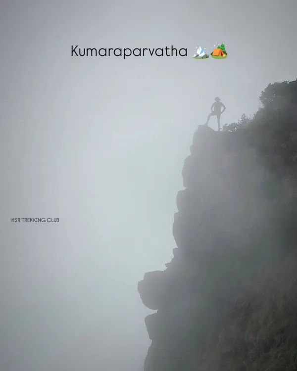A lone trekker stands silhouetted against the fog on a cliff edge at Kumaraparvatha. This image perfectly captures the moody and epic scale of this challenging trek.