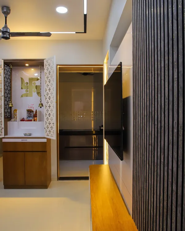 A beautifully crafted mandir with intricate jali-cut doors, integrated lighting, and storage. It is positioned thoughtfully within the living area, creating a serene spiritual corner.