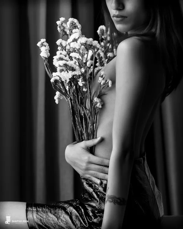 An artistic and intimate black and white portrait. Using a bouquet to create shape and shadow, this image is a perfect example of fine art boudoir photography, focusing on sensuality and mystery.