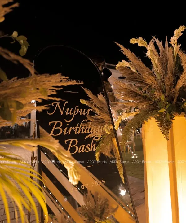 First impressions matter. For this birthday bash, we created a chic welcome sign on black acrylic, framed with pampas grass and lit by warm uplighting to set a sophisticated and celebratory mood from the very beginning.