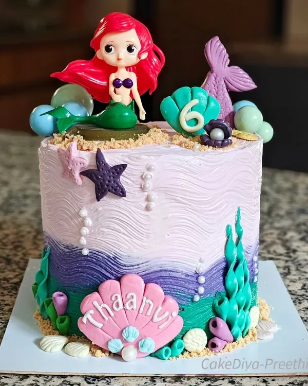 A mer-mazing cake for a mermaid lover. This 10-inch tall, double-barrel chocolate buttercream cake is decorated with waves, edible sand, and plenty of under-the-sea fondant details.