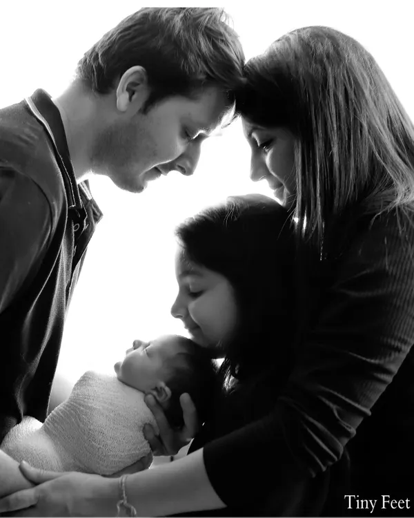 A beautiful black and white portrait of a family of four adoring their newest member. These newborn family sessions are perfect for capturing the love that fills the room.