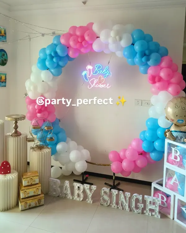 A classic baby shower setup featuring a full balloon ring in pink, blue, and white. The scene is completed with a "Baby Shower" neon sign, custom "BABY SINGH" lettering, and transparent 'B-A-B-Y' blocks, perfect for welcoming the new arrival.