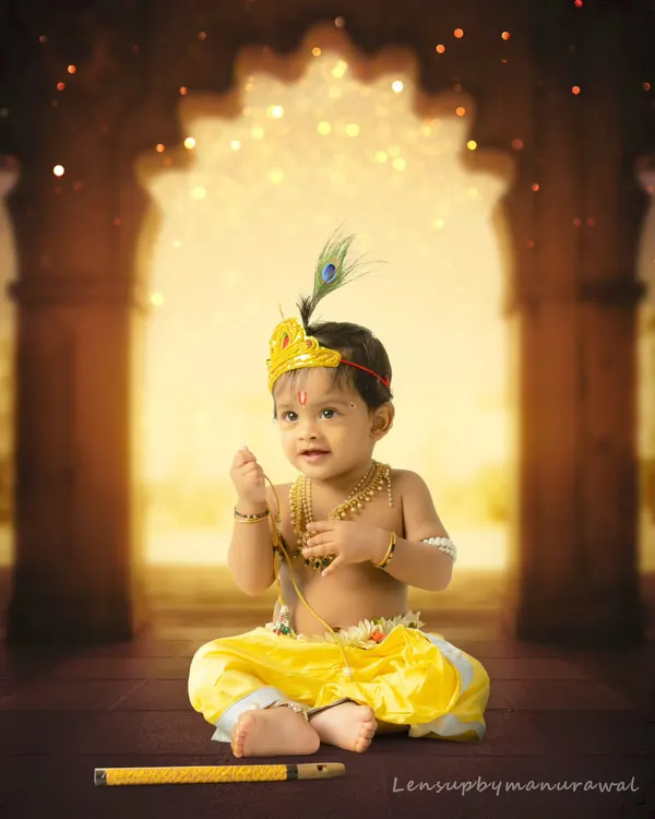 A beautifully composed portrait of a baby boy dressed as little Krishna, sitting in a divine, temple-like setting with a soft, magical glow.