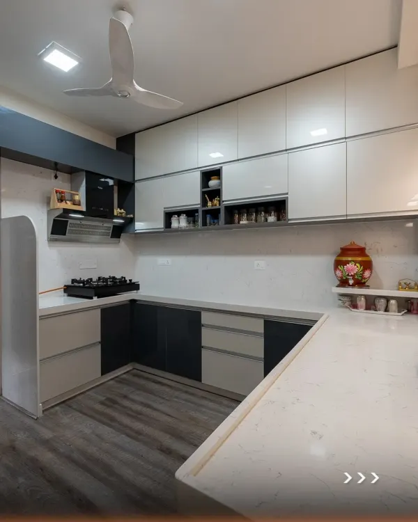 This U-shaped modular kitchen uses a dual-tone scheme of dark grey and off-white to create a sophisticated look. The layout provides ample counter space and an efficient work triangle, making it ideal for busy households.