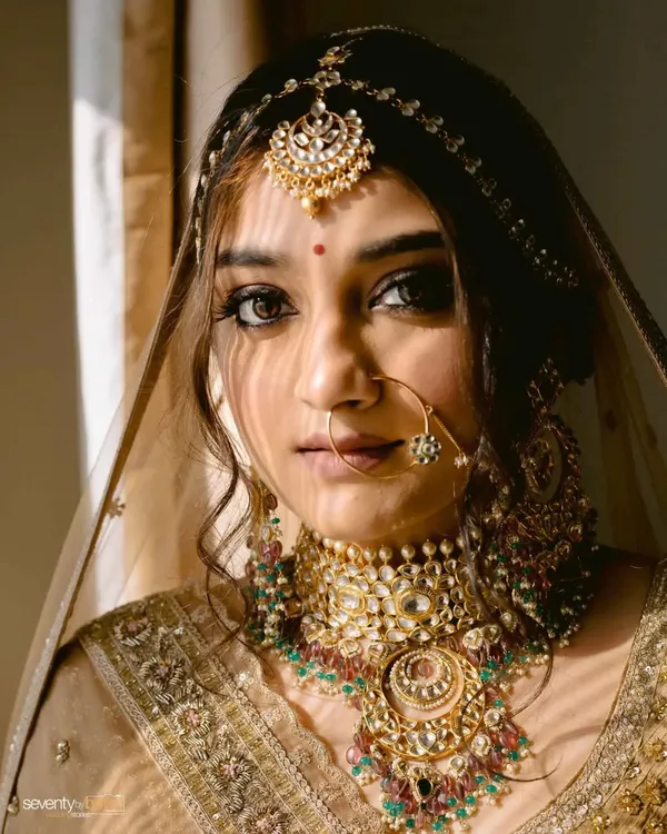 A bride bathed in a sliver of sunlight, the shadows creating a dramatic and captivating portrait. Her gaze is direct, her presence powerful.