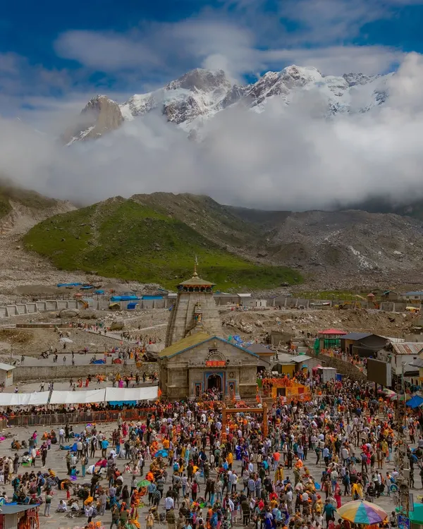 The sacred Kedarnath Temple in Uttarakhand, with the majestic snow-capped Himalayas as its backdrop. The crowd of pilgrims shows the immense faith this place inspires.