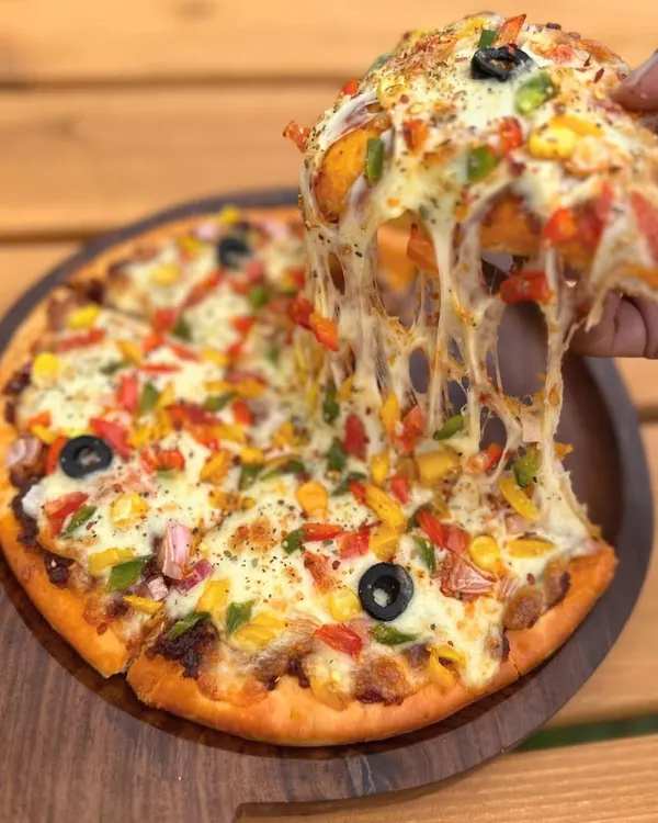 Nothing beats a cheesy pizza pull! Our Veggie Delight Pizza is a favorite among human guests at the "Think Pawsitive" Cafe.