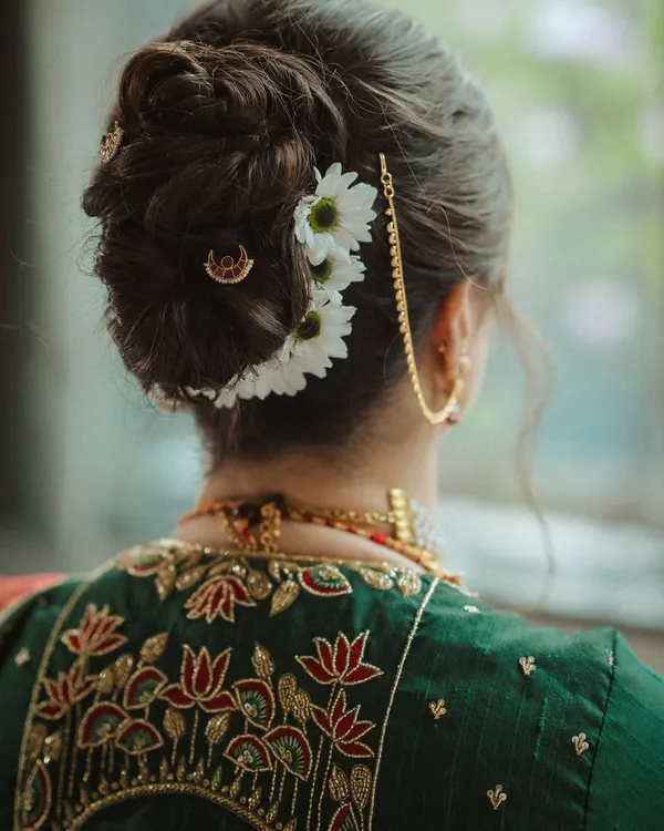 This is the hero item. A classic Maharashtrian bridal bun, intricately woven and adorned with fresh flowers and a traditional hairpin. This style is a perfect example of timeless elegance, designed to be stunning from every angle and hold beautifully through the ceremony.
