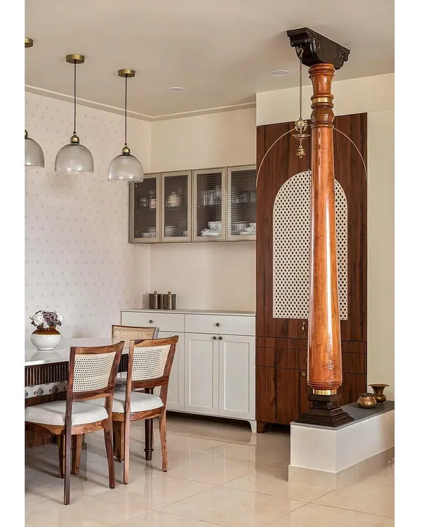 This dining area pays homage to the client's heritage with traditional wooden columns and a 'katte' bench. A discreet puja unit is hidden behind CNC jali doors, seamlessly integrating spirituality into the design.
