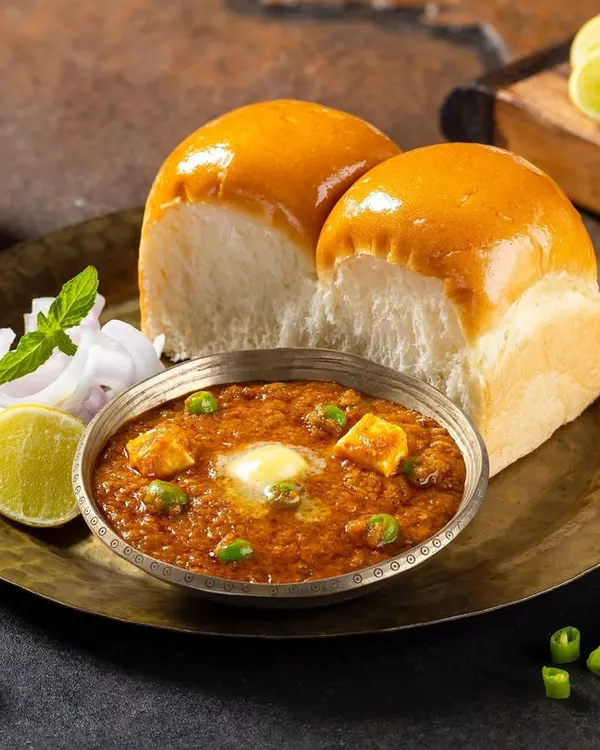 A classic Mumbai Pav Bhaji, styled with fresh garnishes and soft pav buns for Grover Sweets. I used specific lighting to emphasize the rich texture of the bhaji and the glossy butter, creating a highly appetizing hero image for their menu. This is a great example of Indian street food photography.