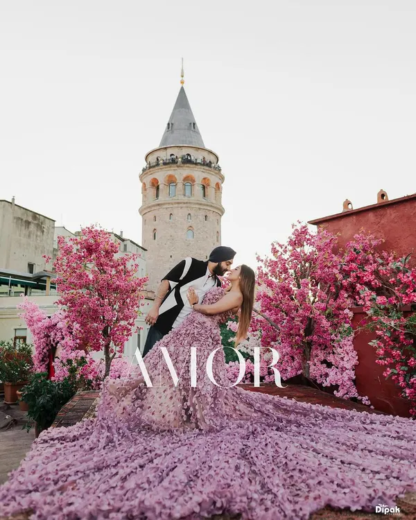 A stunning pre-wedding portrait in front of the Galata Tower in Istanbul, framed by beautiful pink blossoms. This image captures the essence of a romantic, European-style destination shoot.