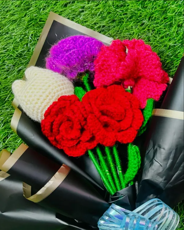 This custom bouquet features bright red roses, a white tulip, and other colorful flowers, all handmade and wrapped in elegant black paper for a striking contrast.