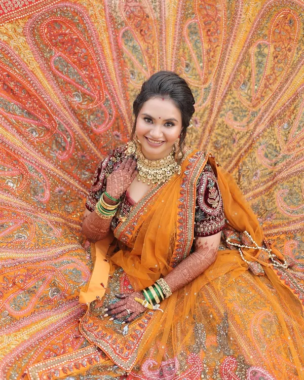 A breathtaking full-length shot of my bride in her stunning orange lehenga. I aimed for a look that was as grand and beautiful as her attire, focusing on radiant skin and classic bridal makeup.