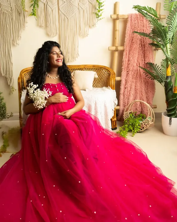A joyful, candid moment in a vibrant pink tulle gown. The boho-chic studio setup with natural light creates a relaxed and happy atmosphere.