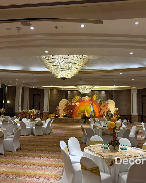 A wide view of the entire banquet hall transformed for a Lion King celebration. The grand stage is the focal point, with themed tables ready for guests to enjoy the party.