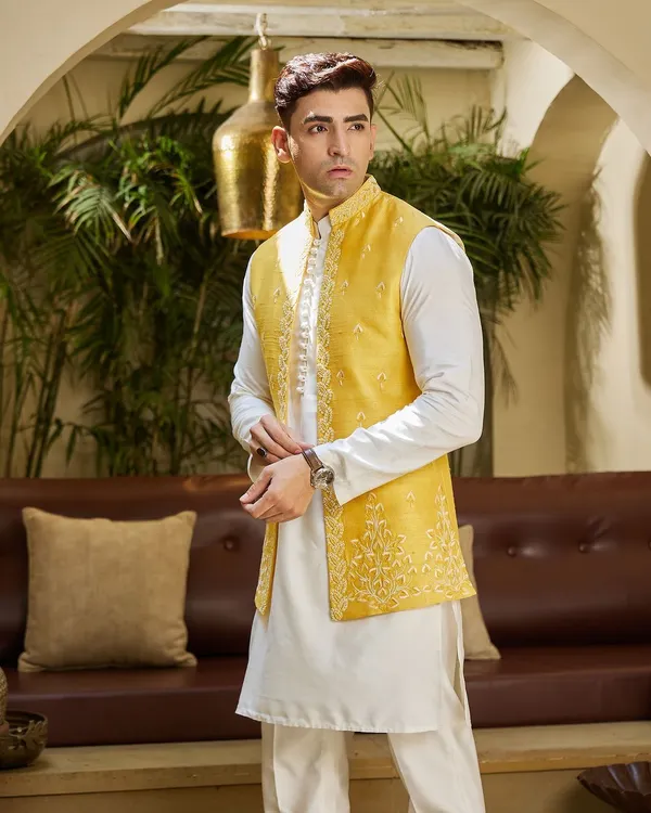 Embrace the spirit of the Haldi ceremony with this vibrant yellow embroidered jacket. Paired with a simple white kurta, it's a look that is both festive and sophisticated.