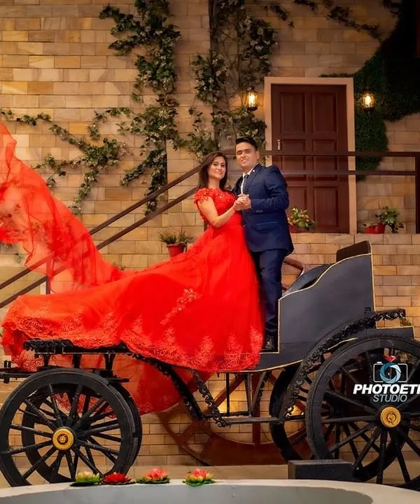 A fairytale moment brought to life with a vintage horse-drawn carriage. The bride's dramatic red gown flows beautifully, creating a stunning, high-fashion pre-wedding photograph.