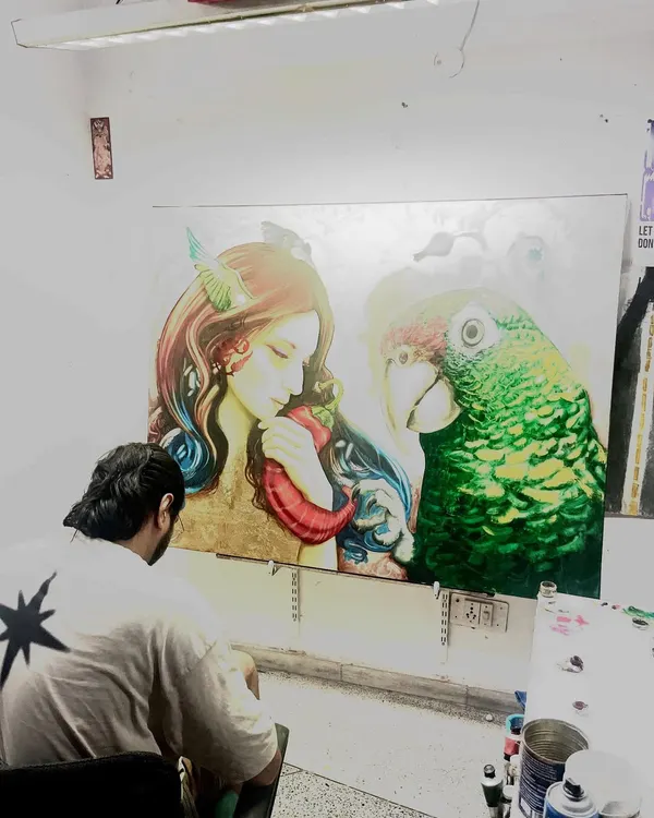 A view from behind my shoulder as I work on the fine details of this large parrot painting. Creating art is a meditative process that requires immense focus and patience.