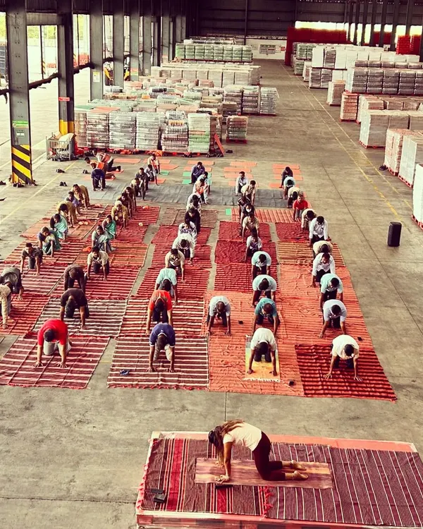 Leading a large corporate yoga class at a Coca-Cola distribution warehouse. This wide shot shows me guiding dozens of employees through a gentle warm-up, bringing a moment of calm to their busy workday.