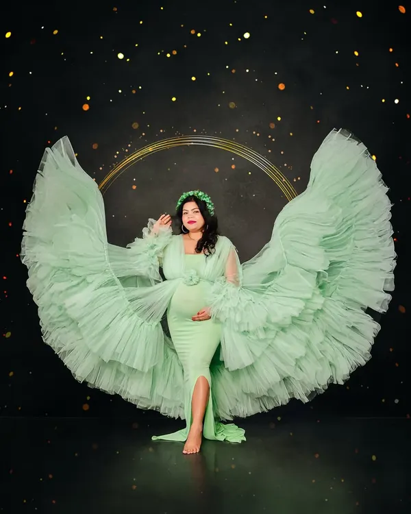 A solo portrait celebrating the mother-to-be in our stunning mint green ruffled gown. We create these angelic, wing-like effects by expertly tossing the fabric, resulting in a truly magical and empowering image against a dark, starry backdrop.