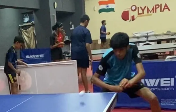 A young player executing a low shot during a match. This image represents the focus and determination of our athletes, like Vivyan Gada and Trissha Ludbe, who secured medals in the TSTTA District Ranking Tournament.