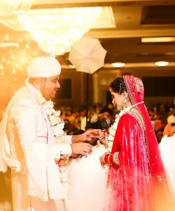 A magical moment during the Varmala ceremony. The couple is surrounded by a dreamy cloud effect and golden light from sparklers, creating an unforgettable, fairytale-like image.