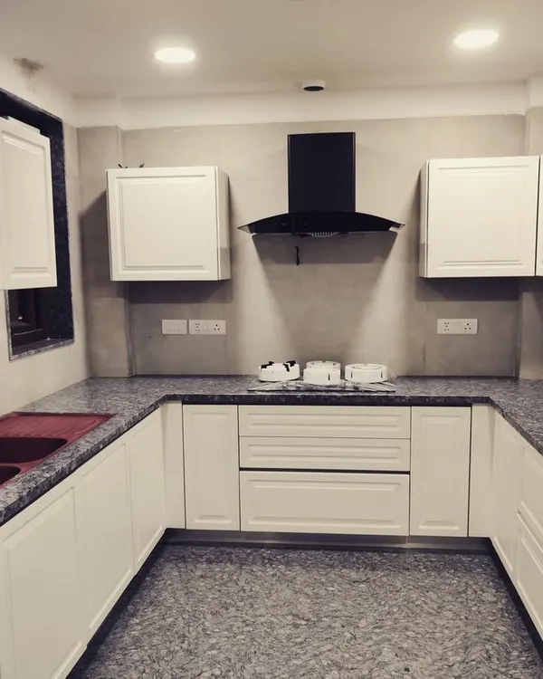 This is the finished U-shaped kitchen in our Gurgaon DLF project. The classic white cabinets provide ample storage, while the granite countertop and floor are chosen for their durability and ease of maintenance.