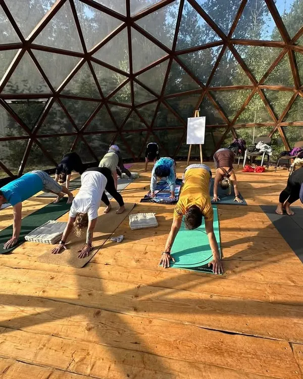 Welcome to our practice. Here, inside a sunlit dome surrounded by nature, we move and breathe together. This is a space where we connect with ourselves and each other, finding strength in community and stillness in movement.