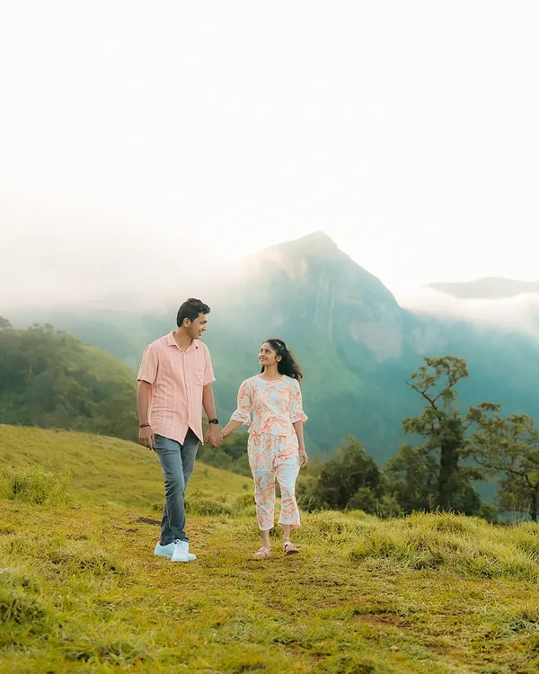 A couple walks hand-in-hand against a stunning backdrop of misty mountains. This is the kind of epic, scenic pre-wedding photography I specialize in.
