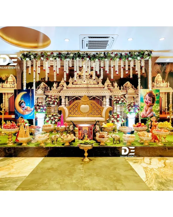 A truly grand and royal baby shower setup designed to look like a temple gopuram. The stage is filled with traditional offerings, Marapachi dolls, and a regal seat for the mother-to-be.