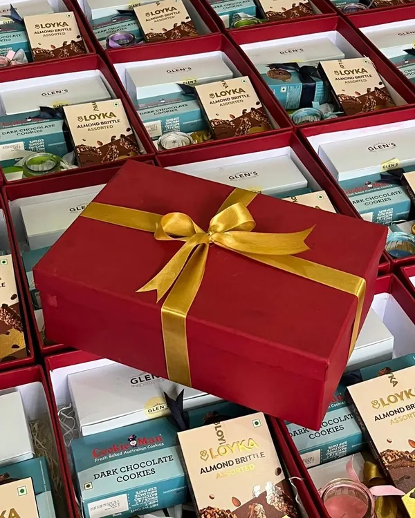 We manage large-scale corporate orders with precision. Here, hundreds of festive gift boxes are being prepared, with one elegant red and gold box highlighting the final presentation.