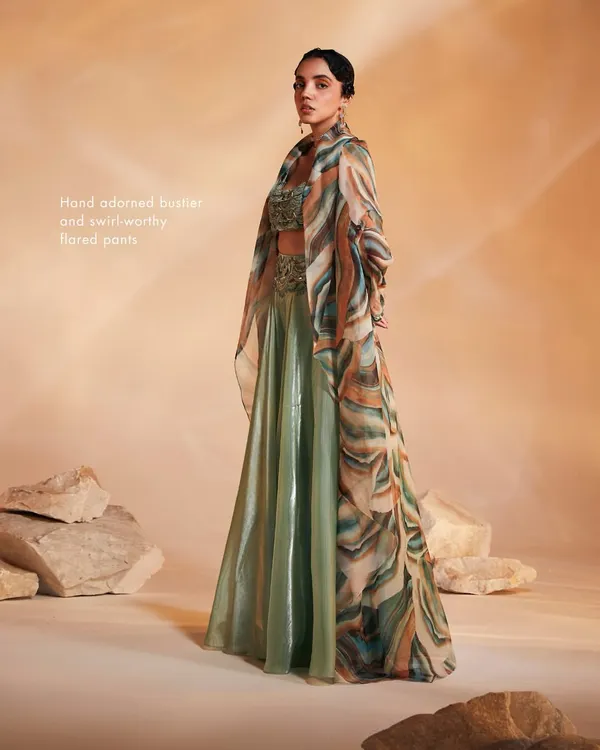 The Adoree Cape Set in a striking sage green with a multi-color printed oversized cape. The hand-adorned bustier and flared pants create a perfect balance of modern and traditional.