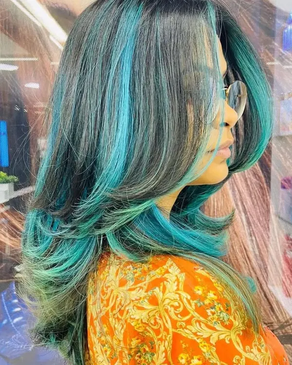This is a fantastic example of our creative color work. The vibrant turquoise highlights are expertly blended with the client's dark base color for a bold, fashion-forward look.