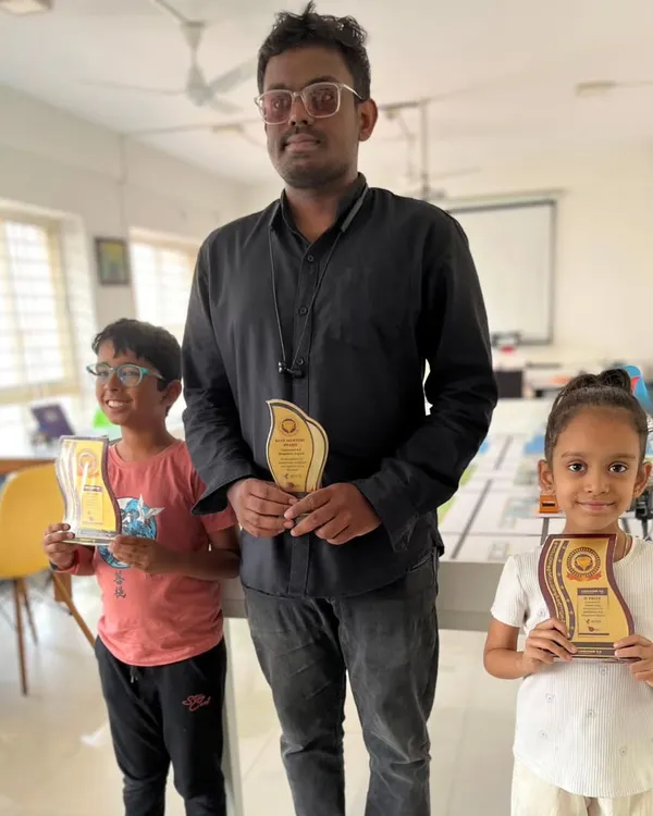 Two of our young champions proudly display their trophies from the Codeavour 6.0 robotics competition alongside their mentor. This highlights our success across different age groups.