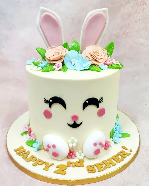 This Happy Bunny Cake is pure pastel joy, featuring a sweet bunny face, floral crown, and little paws, perfect for a second birthday.