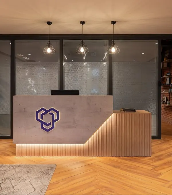 The reception desk at YOUNION Office, where a concrete-finish desk with integrated lighting and herringbone wood floors create a modern and welcoming first impression.