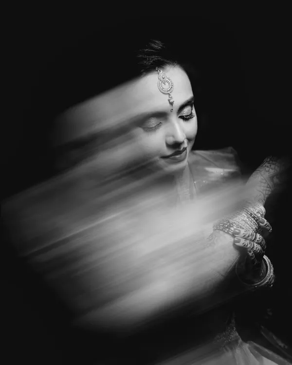 A stunning black and white bridal portrait using a slow shutter speed to create a motion blur effect. This artistic technique adds a sense of movement and ethereal beauty to the image.