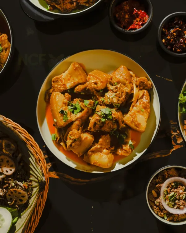A top-down shot of my tender pork curry, surrounded by various Manipuri side dishes and chutneys.