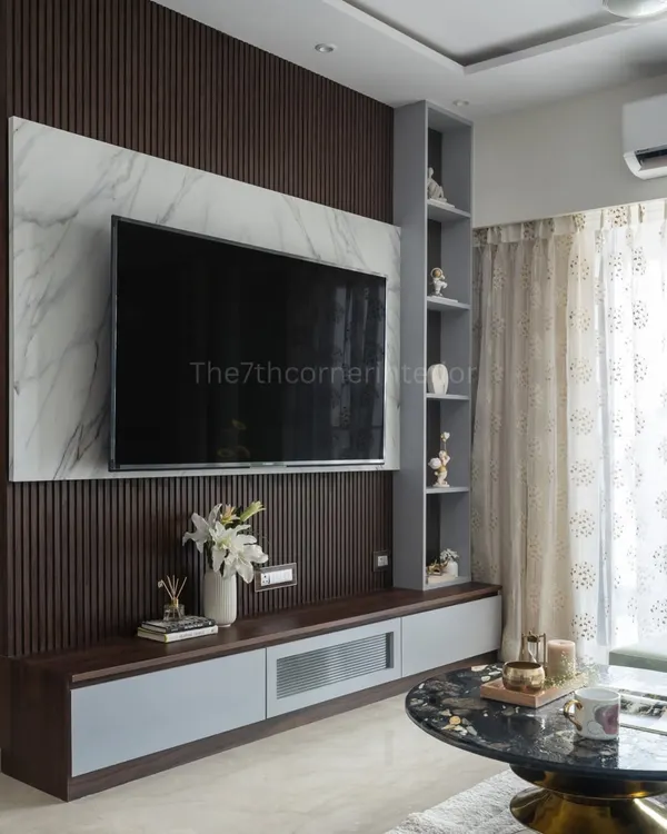 This custom TV unit is a statement of style, featuring a backlit Italian marble panel, sleek handle-less drawers, and an integrated niche with a tinted mirror for displaying art.